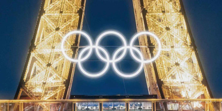 Olympic rings displayed on a tall structure against a dark sky